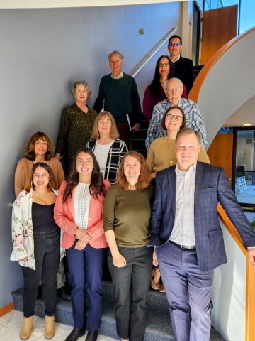 Photo of the NCHEMS staff from February 2024. Photo includes a small group of diverse people on the steps of a staircase; group consists of four  men and nine women. 