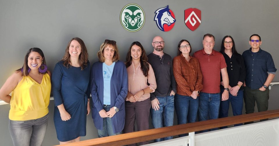 Photo of NCHEMS staff in front of a wall with a sign reading "CSU SPUR". The team (left to right) shows: Jacquelyn Villa, Louisa Hunkerstorm, Stacey Zis, Sarah Torres Lugo, Dan Armour, Sarah Pingel, Brian Prescott, Johnna Clark, and Artemio Cardenas.